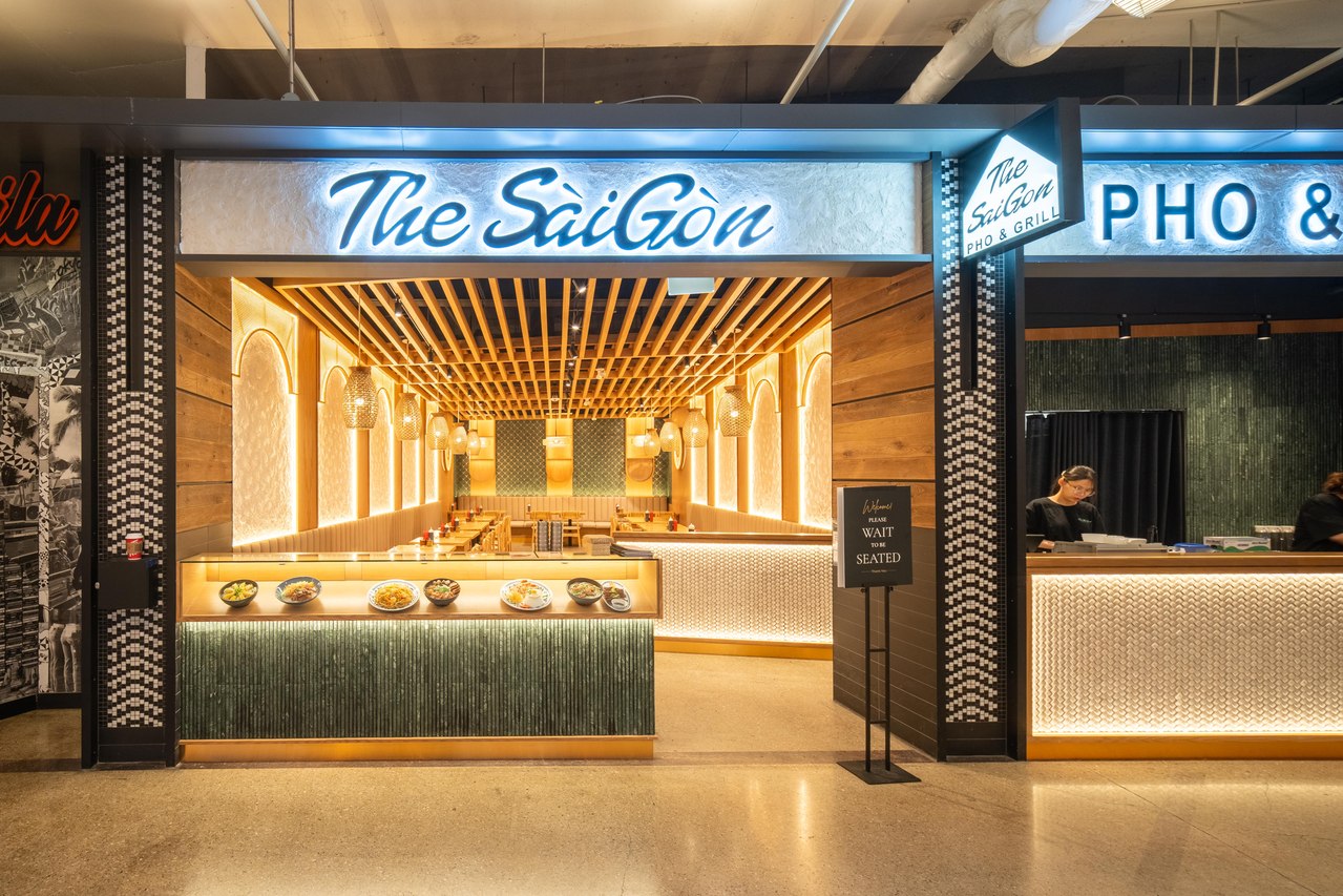 Restaurant entrance with illuminated signage, wood ceiling details and a view into the dining space.
